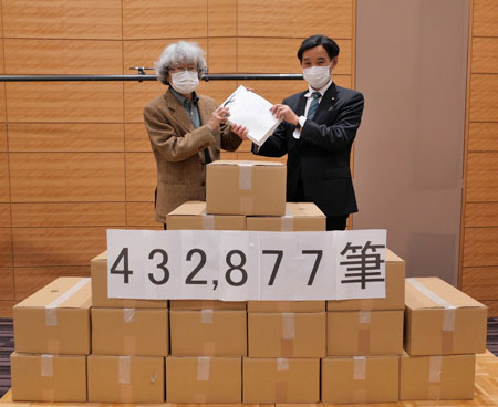 よびかけ人の鎌田慧さん（左）から署名を受けとる山崎衆議院議員（3月5日・東京）